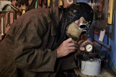 Solunum cihazı ve steampunk tarzı gözlüklü bir adam basınç göstergesi, silindir ve post tapokalipsis konseptiyle çalışır..
