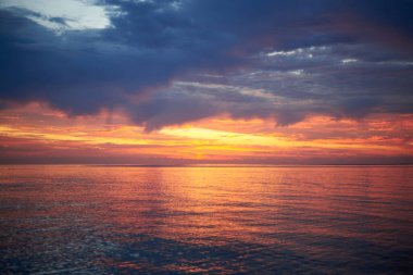 Şafak vakti güzel bulutlu gökyüzü, sakin deniz suyu, manzara.