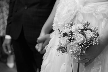 Gelin ve damat birbirlerinin elini tutarlar, gelinin parmağında altın bir yüzük, düğün günü, siyah ve beyaz fotoğraf..