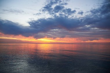 Denizde bulutsuz bir gökyüzünde gün batımı, ufukta bekleyen gemiler....