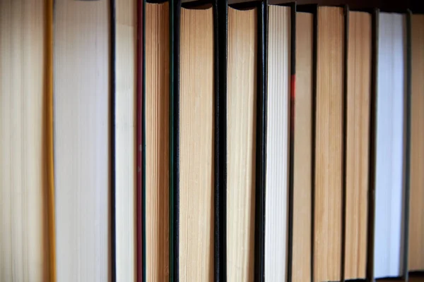 Book spines lined up on the shelf, close-up, learning and education concept.