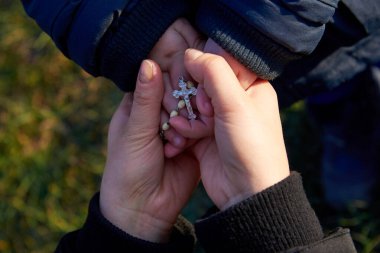 Anne ve küçük oğul bir Hıristiyan dini kavramı ile el ele tutuşuyorlar..