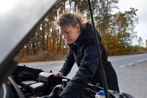 Ceketli Bir Kadın Yolda Bozuk Bir Arabayı Tamir Etmeye Çalışıyor — Stok fotoğraf