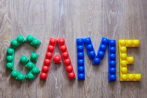 The word Game laid out from large pieces of constructor on a wooden background.