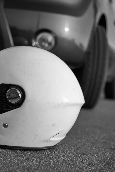 Photo of car and motorcycle helmet on the road, the concept of road accidents, black and white photo.