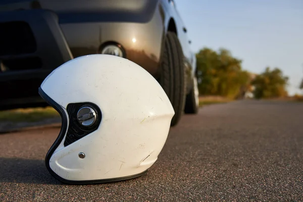 Photo of car and motorcycle helmet on the road, the concept of road accidents.