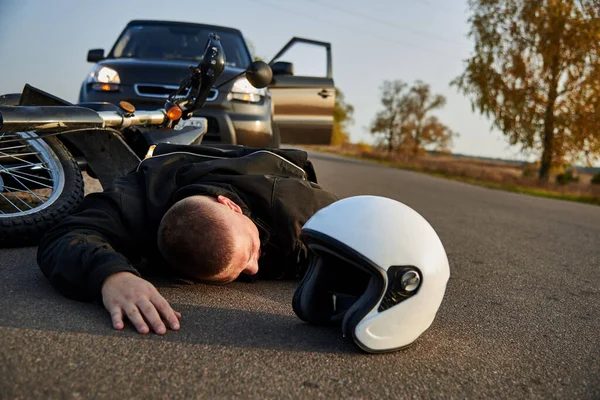 Bir Motosikletçi Asfaltta Bir Motosiklet Arabanın Yanında Yatıyor Trafik Kazalarının — Stok fotoğraf