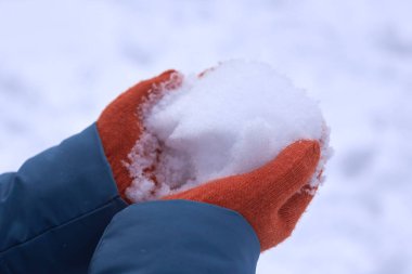 Turuncu eldivenli kadın elleri kar tutar, kış zamanı..