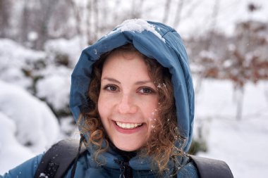 Parkta kışın ceketli, gülümseyen güzel bir kadının portresi..