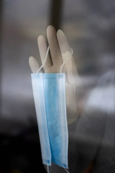 戴橡胶手套的女人的手在窗前拿着医疗面罩 在验尸过程中自我隔离 在家中隔离 — 图库照片
