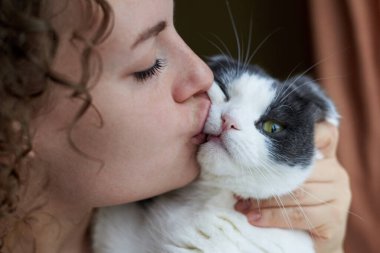 Kadın sevimli kedisine sarılıp öpüyor, yakın plan, evcil hayvanlarla arkadaşlık teması..