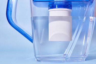 Mavi arka planda ev kullanımı için su filtresi, sağlıklı yaşam tarzının teması.