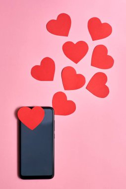 Akıllı telefondan fırlayan kağıt kalpler, üst görünüm, Sevgililer Günü, aşk ve teknoloji konsepti.