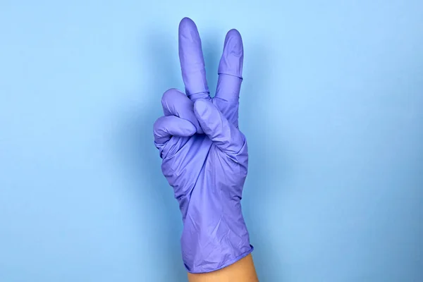 Egy Női Kéz Orvosi Kesztyűben Győzelem Gesztusát Mutatja Kék Alapon — Stock Fotó