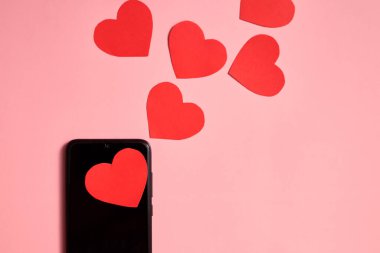Akıllı telefondan fırlayan kağıt kalpler, üst görünüm, Sevgililer Günü, aşk ve teknoloji konsepti.