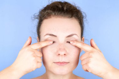 Yüz egzersizi yapan güzel bir kadın, yüz bakımı, kırışıklıklara karşı kendine masaj ve yaşlılık, cildin güzelliğine önem verir..