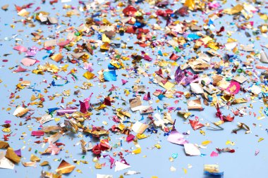 Mavi arka planda parıldayan parlak renkli konfeti, bayram teması ve doğum günü teması.