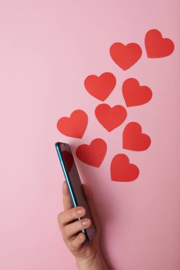 Akıllı telefondan uçan kağıt kalpler, üst görüş, bir kadının elinde Sevgililer Günü, aşk ve teknoloji konsepti..