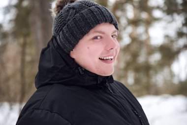 Kış ormanında şapkalı ve ceketli bir gencin portresi..