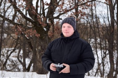 Kış ormanında ceketli ve şapkalı bir adam..