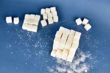 Mavi zemin üzerinde beyaz şeker küpleri yığını.