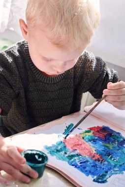 Üç yaşında bir çocuk guaj boyası, eğlence ve çocuk gelişimi ile resim yapıyor..