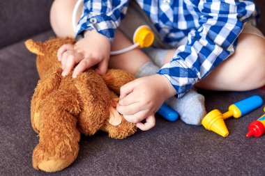 Küçük bir çocuk oyuncak ayıya sıva yapıştırıyor, doktorculuk oynuyor, yakın plan..