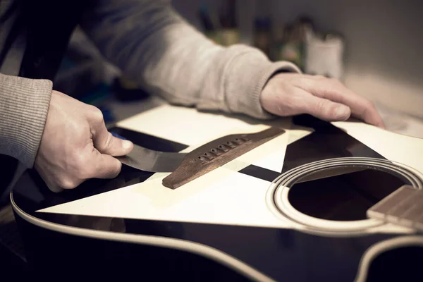Trabalhador Serviço Repara Uma Guitarra Com Uma Ferramenta Foto Tonificada — Fotografia de Stock
