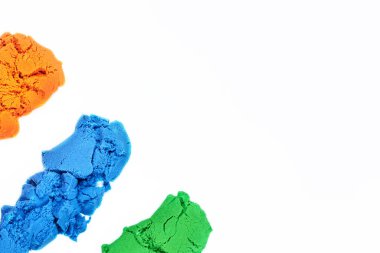 Beyaz arka planda parlak kinetik kumların farklı renkleri, kopyalama alanı, çocuk eğlencesi.