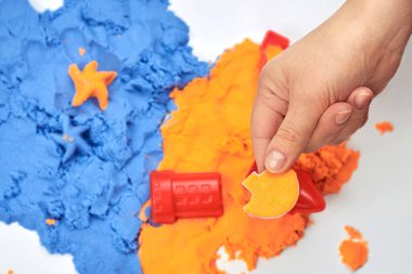 The girl's hand holds a sand beads filled with bright kinetic sand, children's entertainment.