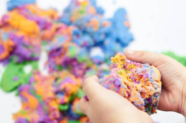 The boy's hands are squeezing bright kinetic sand, children's entertainment.