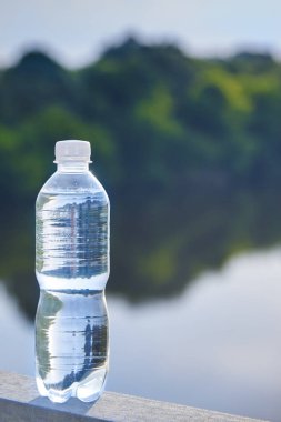 Pure transparent drinking water in a plastic bottle against the background of the river.
