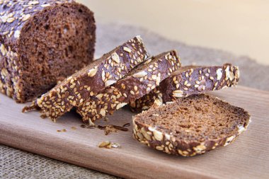 Çavdar ekmeği dilimlenmiş, ayçekirdeği, keten tohumu ve tahtanın üstünde yulaf ezmesi..