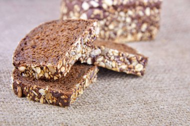 Çavdar ekmeği dilimlenmiş. Üstünde ayçiçeği tohumları keten tohumu ve yulaf ezmesi var..