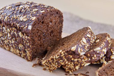 Çavdar ekmeği dilimlenmiş, ayçekirdeği, keten tohumu ve tahtanın üstünde yulaf ezmesi..