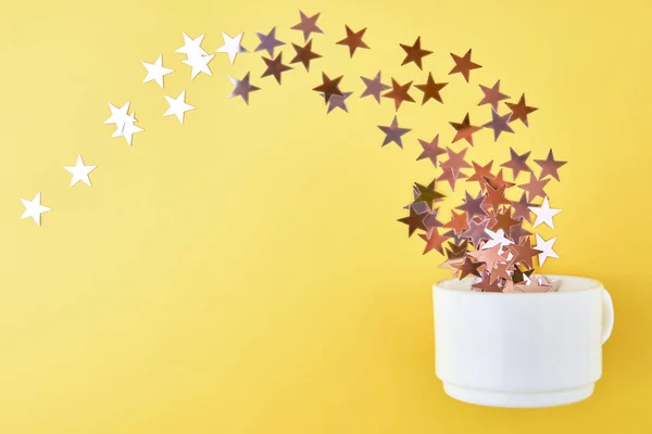 Confetti Estrellas Vuelan Una Taza Sobre Fondo Amarillo —  Fotos de Stock