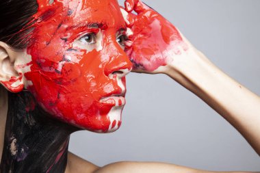 portrait of young beautiful woman posing with red paint at face
