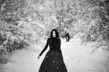 Genç ve güzel bir kadının kış parkında siyah elbiseli pozu.