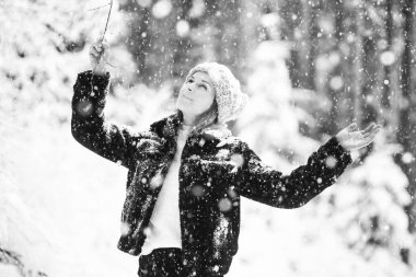 Genç ve güzel bir kadının kış mevsiminde dışarıda poz verdiği siyah beyaz bir portre.