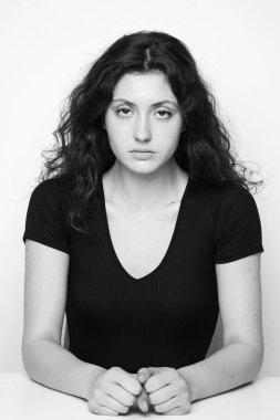 Beyaz arka planda poz veren genç, duygusal, kıvırcık kızın tek renkli portresi.