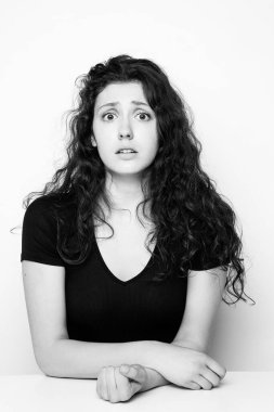 Beyaz arka planda poz veren genç, duygusal, kıvırcık kızın tek renkli portresi.