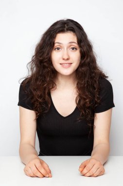 Beyaz arka planda poz veren genç ve duygusal kıvırcık bir kızın portresi.