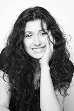 Beyaz arka planda poz veren genç, duygusal, kıvırcık kızın tek renkli portresi.