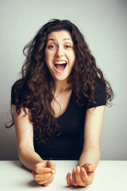 Beyaz arka planda poz veren genç ve duygusal kıvırcık bir kızın portresi.