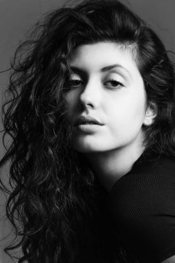 Beyaz arka planda poz veren genç, duygusal, kıvırcık kızın tek renkli portresi.