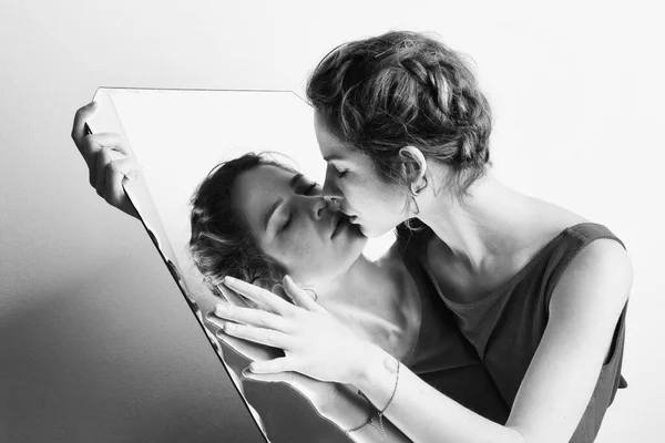 Portrait of the woman with mirror reflection posing in studio