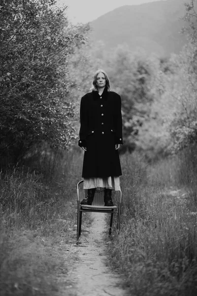 Κορίτσι Ένα Παλτό Στέκεται Στην Καρέκλα Πάνω Στο Φόντο Της — Φωτογραφία Αρχείου