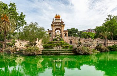 Barselona 'daki Ciutadella Parkı' nda şelaleli muazzam barok çeşmesi, yeşil gölet ve yemyeşil bitki örtüsü.