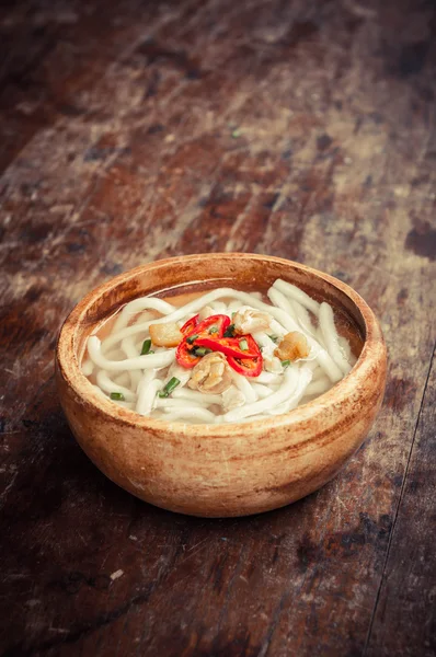 Close-up van udon noedels in houten kom op houten vloer — Stockfoto