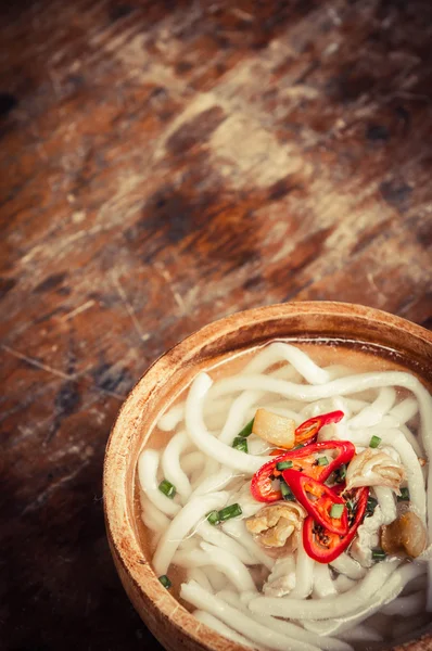 Close-up van udon noedels in houten kom op houten vloer — Stockfoto